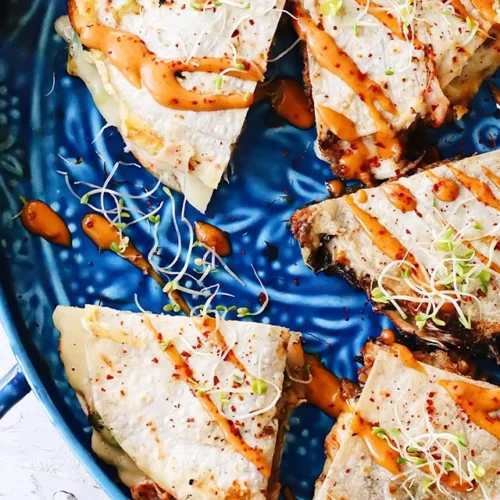 Beef quesadilla served in a blue plate with sauce