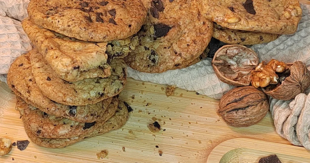 Close up Image of Chocolate Chip Walnut Cookies with chocolate chunks and Walnuts on a wooden food board
