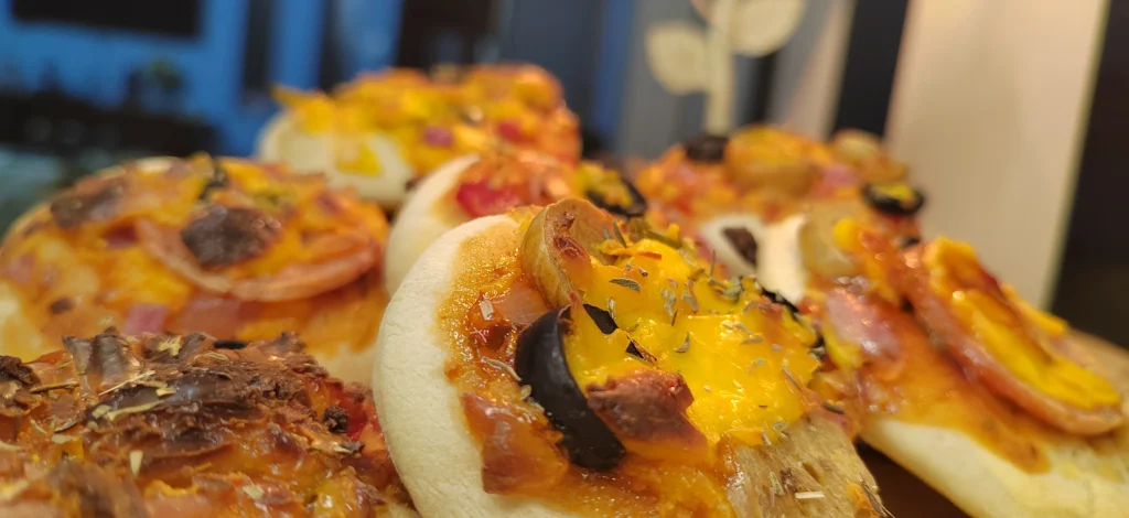 Close up image of homemade mini pizzas with black olives pepperoni and sausages