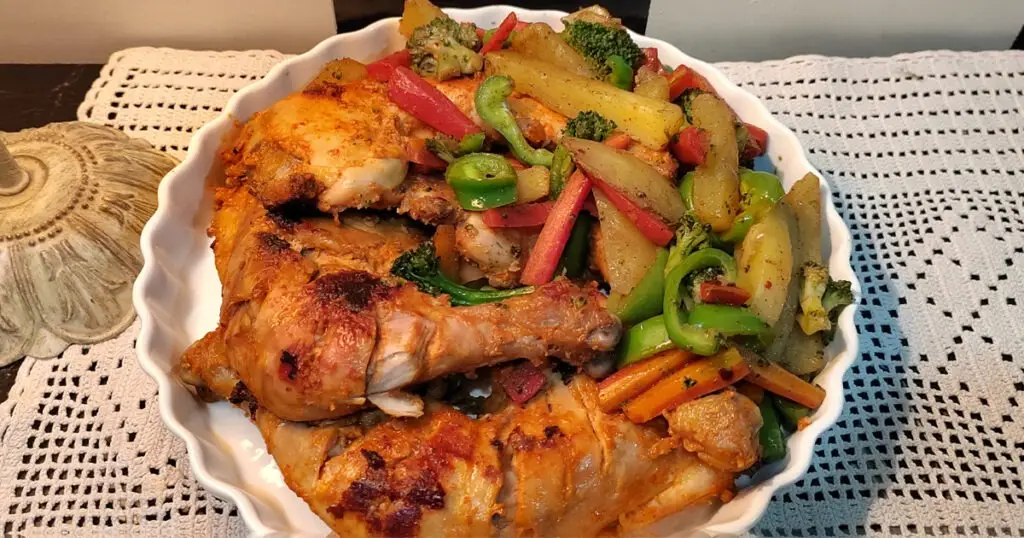 Top view of smoked chicken served with sautéed vegetables placed on a crochet mat besides a lamp