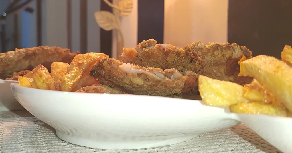 Close up image of air fryer fish and chips served in a white platter