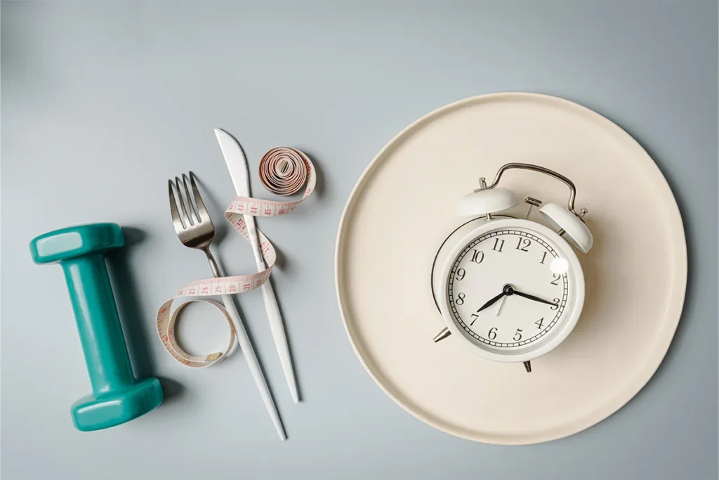Image of plate with a clock, spoon and fork beside the plate with measuring tape and a dumbbell